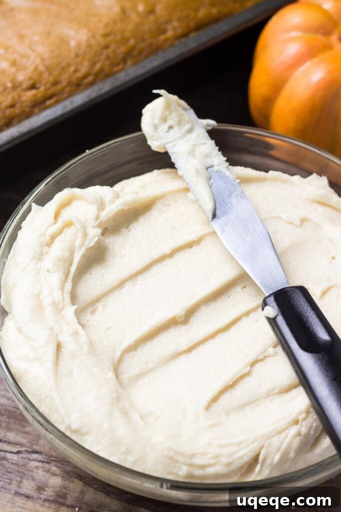 Golden Maple Pumpkin Cake 3 A close-up shot of a thick slice of moist pumpkin cake, topped with a generous swirl of creamy maple frosting, showcasing its beautiful texture and inviting golden-brown crumb. This cake is infused with cinnamon, nutmeg, and cloves, and paired with real maple buttercream.