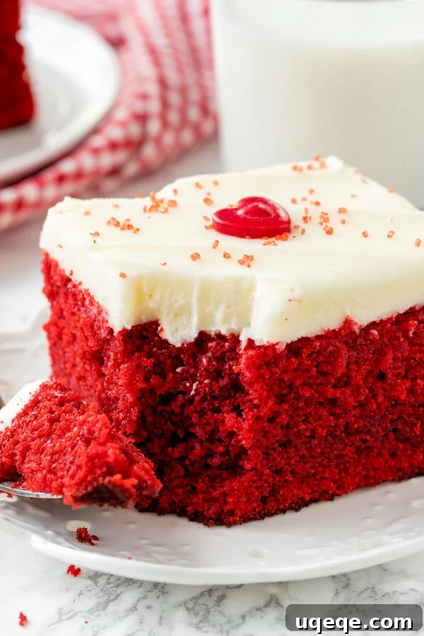 Effortless Red Velvet Delight 6 A slice of red velvet cake with cream cheese frosting on a white plate.