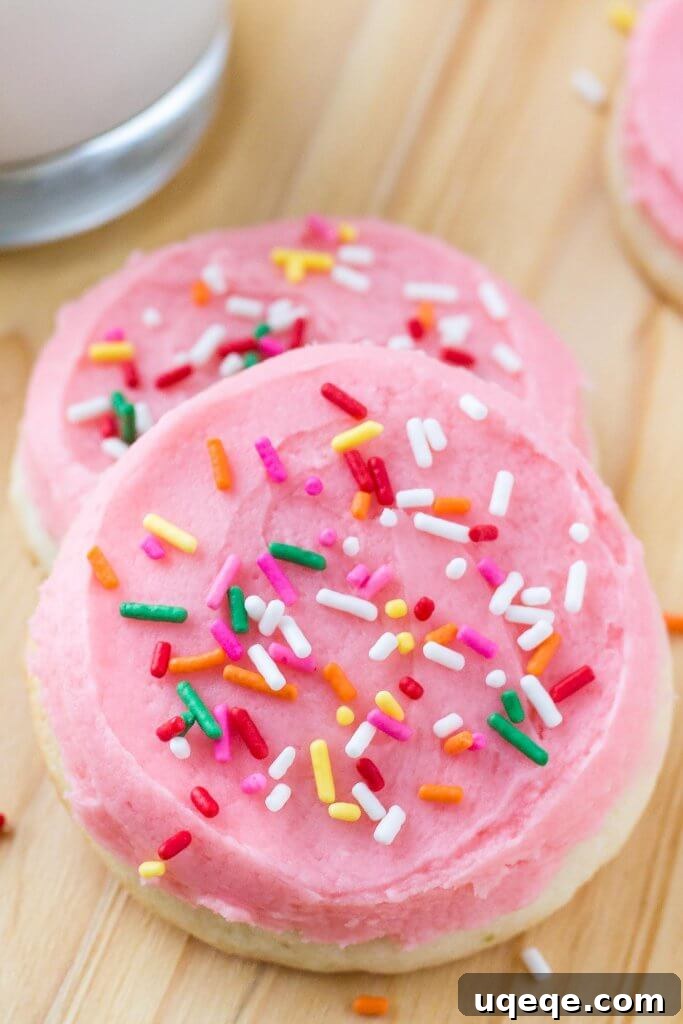 Close-up of a stack of fluffy copycat Lofthouse sugar cookies topped with thick, creamy frosting and vibrant sprinkles, ready for a taste.