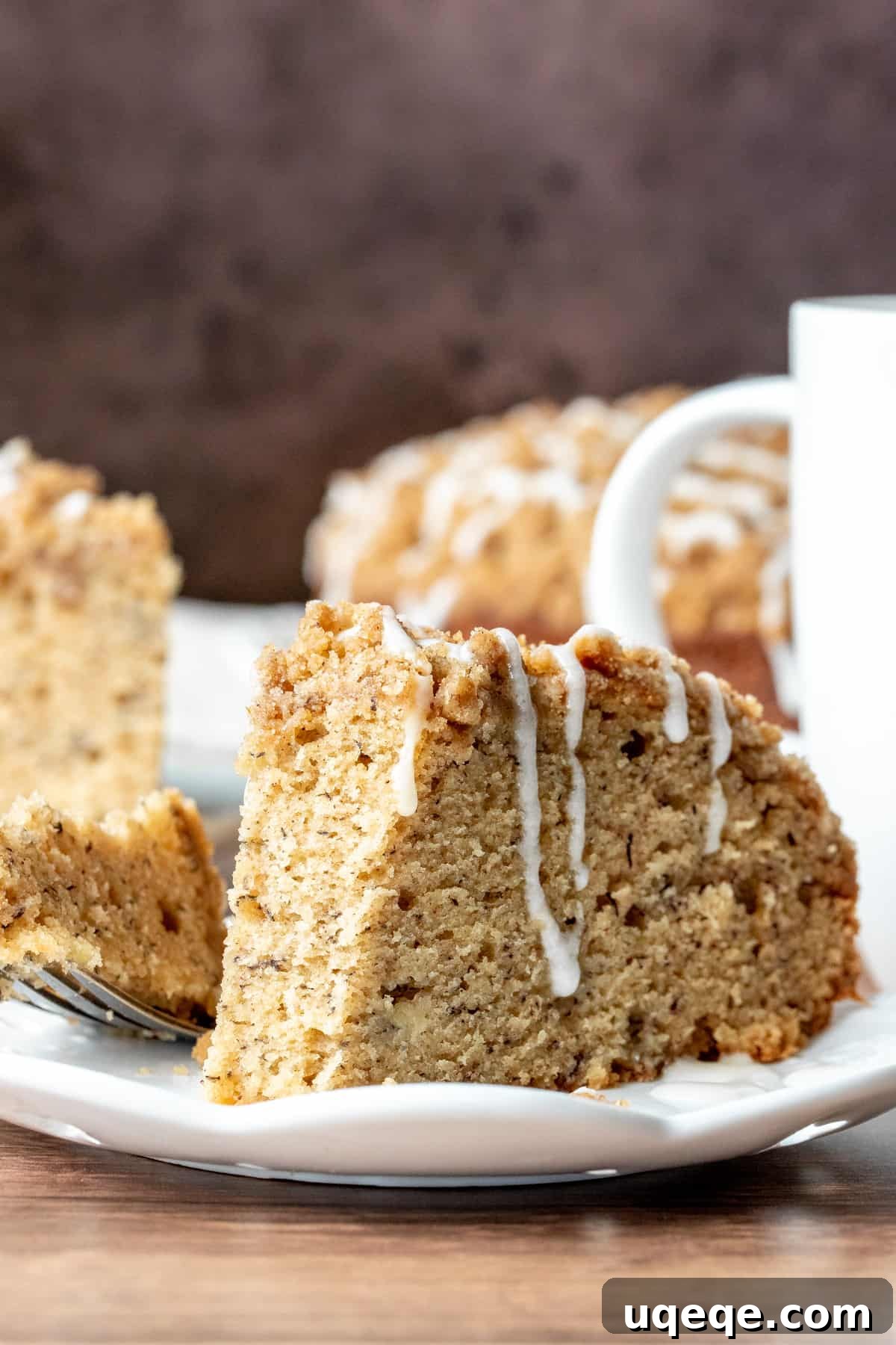 A delectable slice of banana cake with a crunchy streusel topping, a small bite taken out, revealing its moist interior