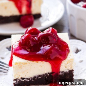 A delicious slice of brownie cheesecake bars topped with vibrant cherry pie filling, showcasing its fudgy brownie bottom and creamy cheesecake layer.