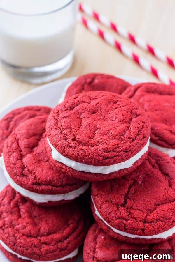 Velvet Crimson Delights 3 A plate of freshly baked red velvet sandwich cookies with cream cheese frosting, accompanied by a glass of cold milk, suggesting a delightful treat.