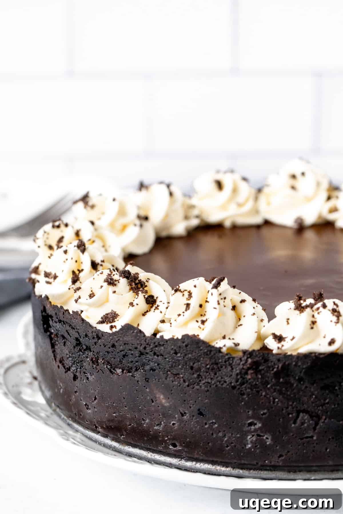 Oreo Obsession Cheesecake 7 9-inch round Oreo cheesecake with chocolate topping and whipped cream around the edges.