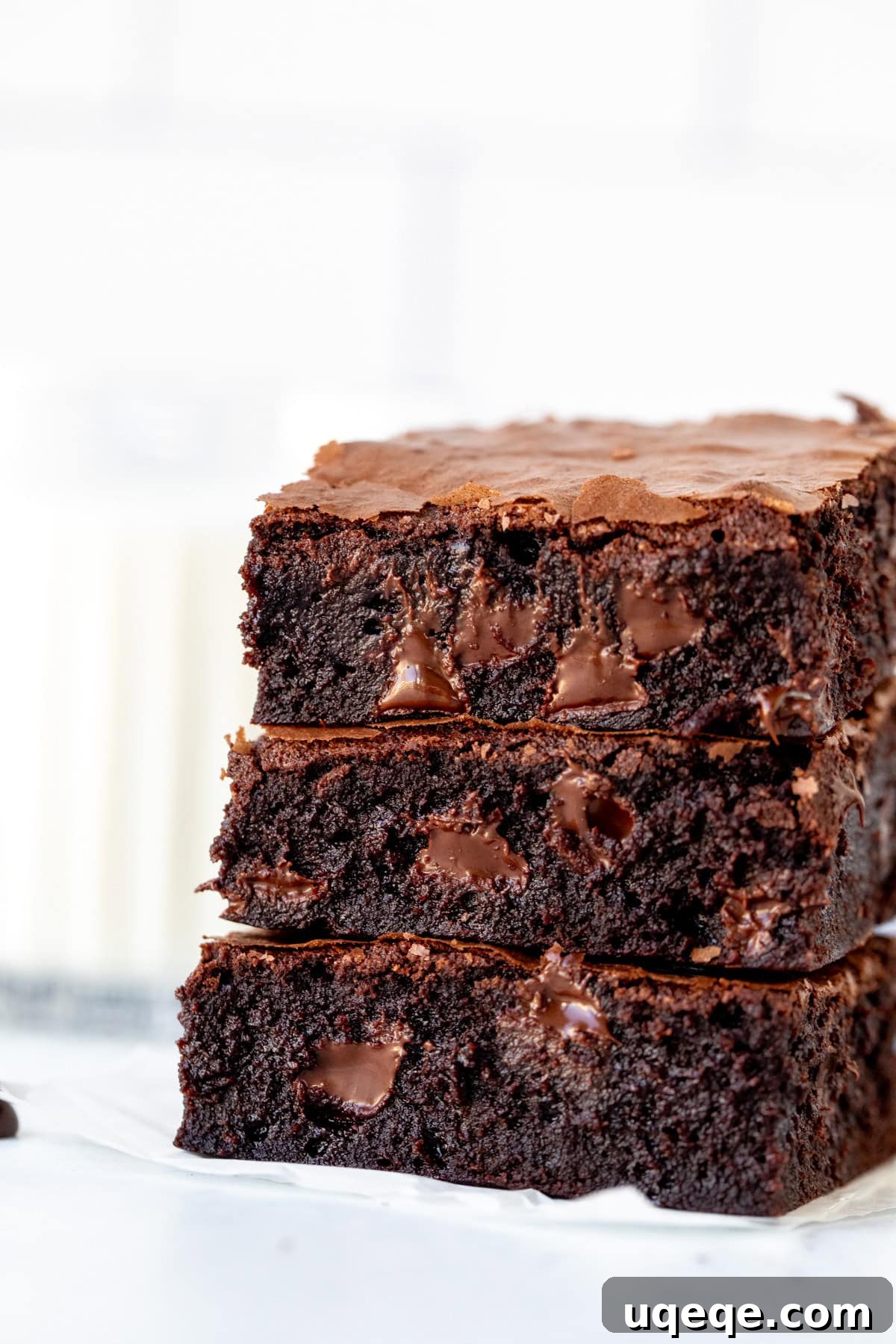 Chocoholic's Dream Brownies 2 Stack of three triple chocolate brownies with a glass of milk, showcasing their fudgy texture and crinkly tops.