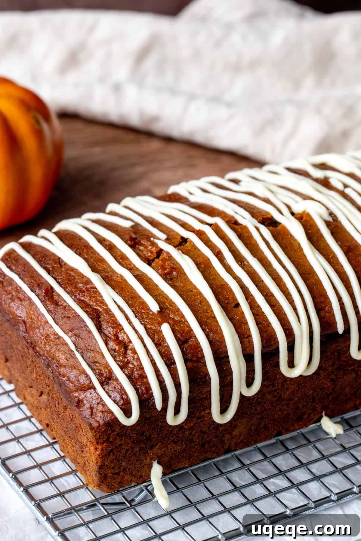 Loaf of moist pumpkin bread drizzled with cream cheese glaze, ready to serve