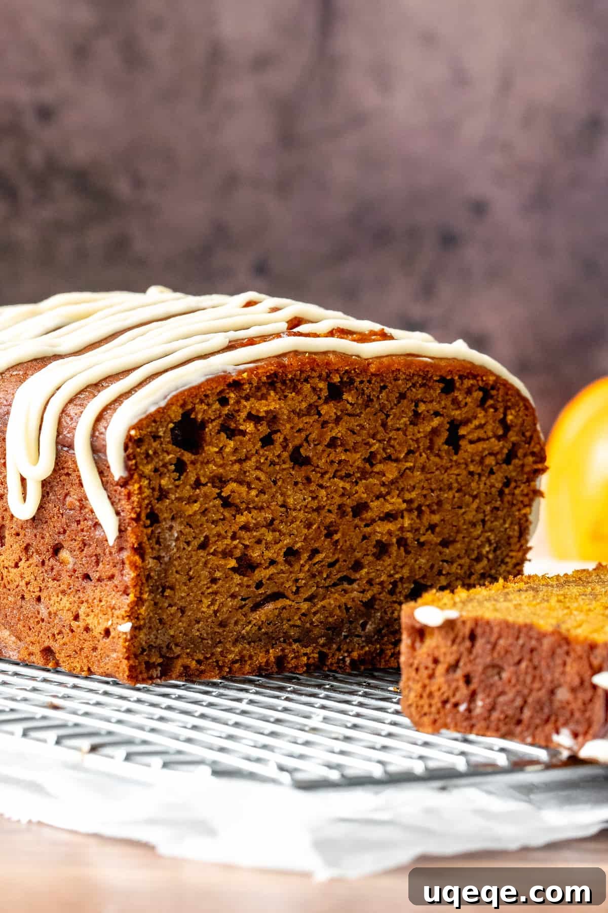 Half of a perfectly baked pumpkin loaf resting on a wire cooling rack