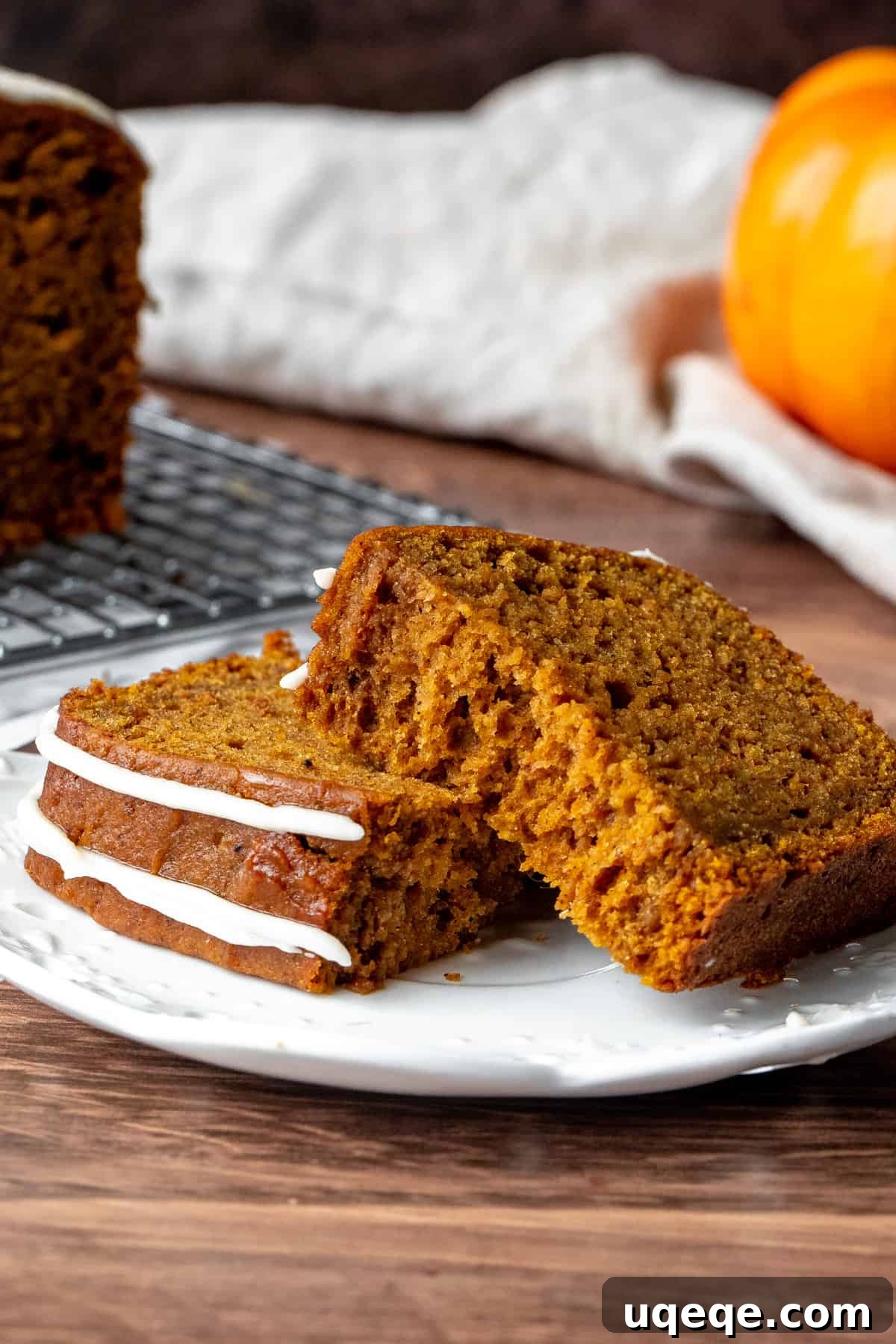 A slice of moist pumpkin bread broken in half, showing its tender crumb and inviting texture