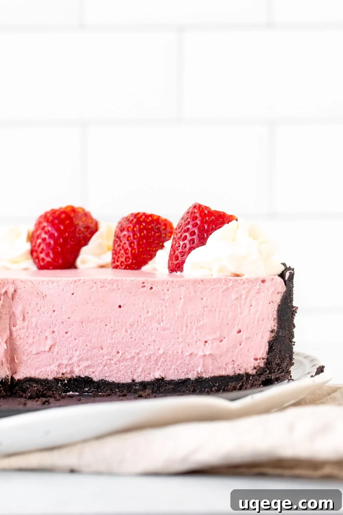 Velvet Strawberry Cheesecake 8 Strawberry cheesecake with Oreo crust with slices cut from the cheesecake