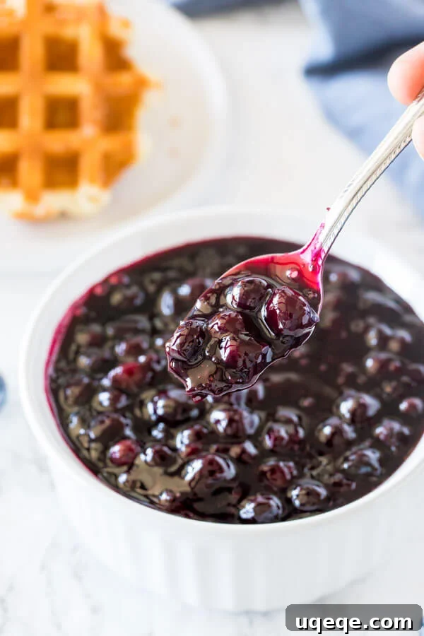 A bowl of homemade blueberry sauce with a spoon taking some out of the bowl.