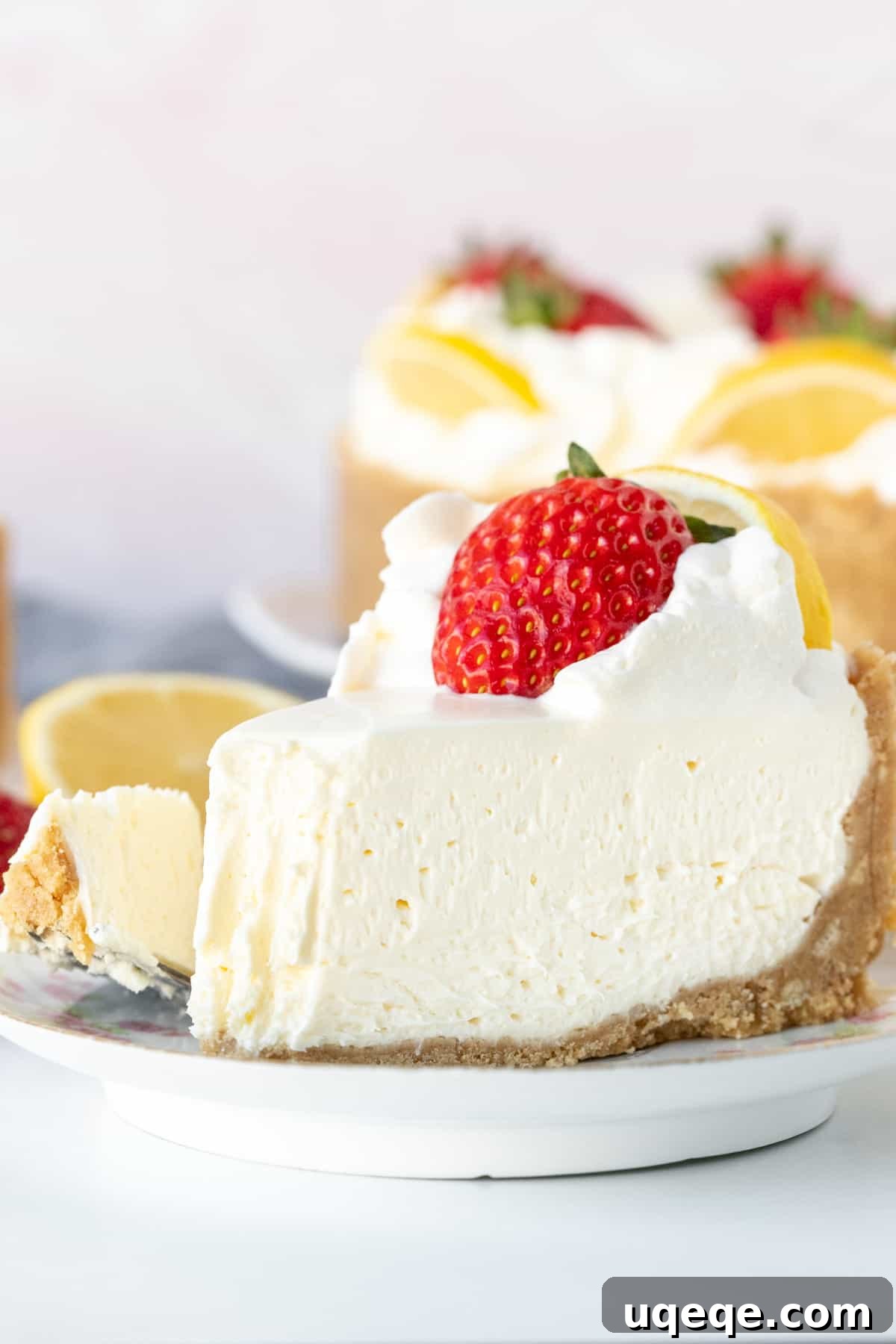 Sunshine Lemon No Bake Treat 9 A tempting slice of no-bake lemon cheesecake, artfully topped with a dollop of whipped cream and a fresh strawberry, with a small bite taken out, inviting a taste.