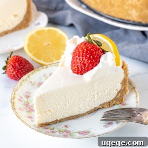 Sunshine Lemon No Bake Treat 10 A close-up of a single piece of no-bake lemon cheesecake, showcasing its golden graham cracker crust, smooth lemon filling, and a fresh strawberry garnish on top.