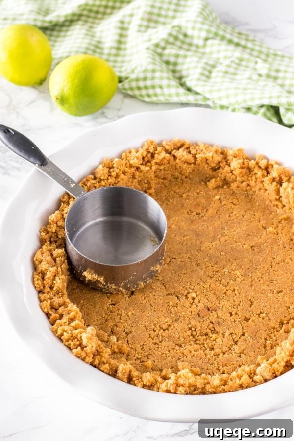 Effortless Key Lime Bliss 4 Making the graham cracker crust for no bake key lime pie by pressing the graham crumb mixture into the bottom and up the sides of the pie plate.