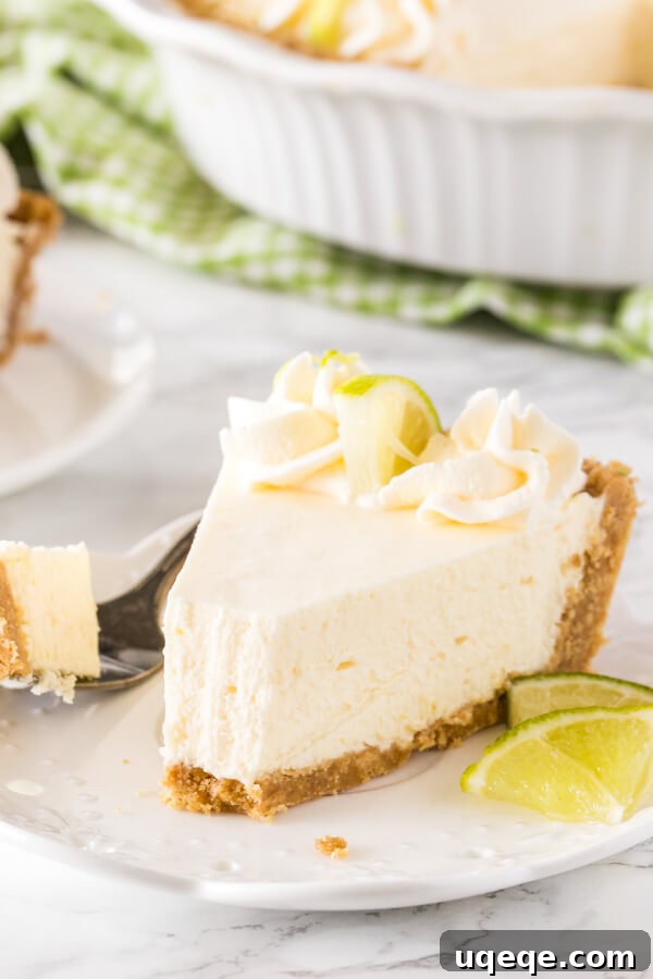 Effortless Key Lime Bliss 6 A slice of key lime pie on a white plate with a bite taken out of it to show the creamy, smooth texture.