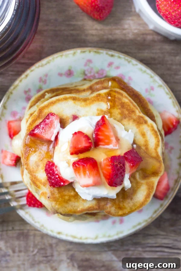 Close-up view of a stack of fluffy strawberry pancakes, highlighting their tender interior and abundant strawberry pieces. A perfect breakfast dish.
