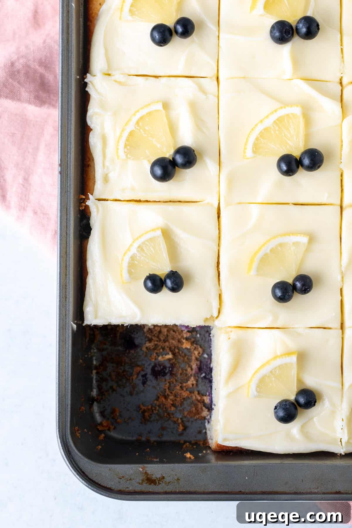 Sunshine Lemon Blueberry Cake 3 A 9x13 inch sheet pan of lemon blueberry cake with cream cheese frosting, artfully cut into squares, showcasing the moist interior.