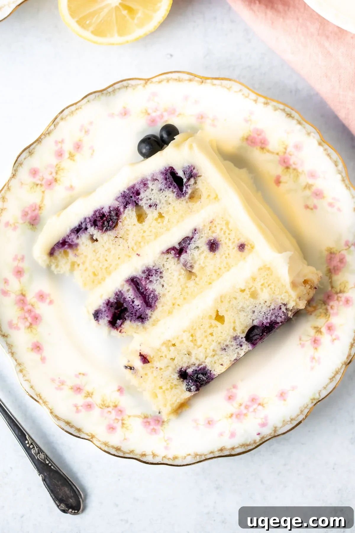 Sunshine Lemon Blueberry Cake 10 A delightful piece of lemon blueberry cake with three layers and generous cream cheese frosting, showing the beautiful layers and fruit.