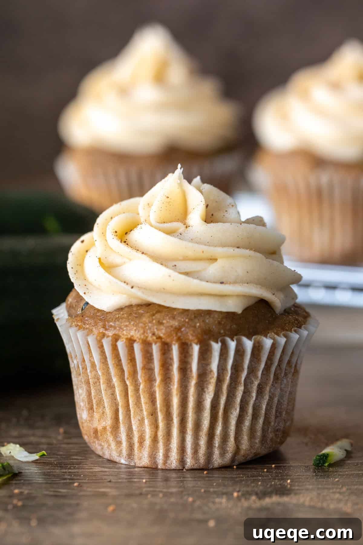 Moist Zucchini Delights with Creamy Dream Frosting 3 A close-up shot of a zucchini spice cake cupcake with a generous swirl of fluffy cream cheese frosting on top, ready to be enjoyed.