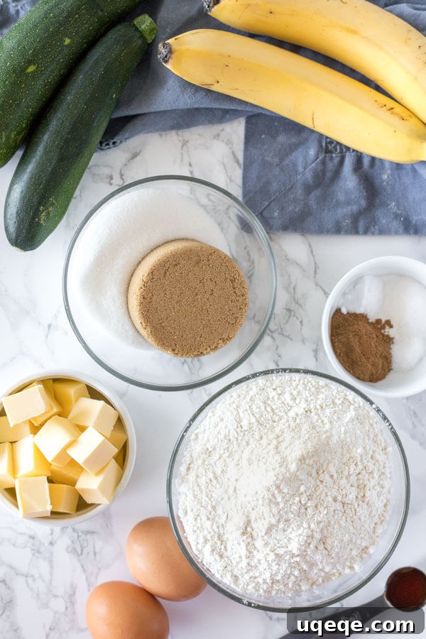 Garden Fresh Zucchini Banana Loaf 4 A flat lay image of all the ingredients needed to make zucchini banana bread laid out on a kitchen counter, including flour, sugar, butter, eggs, bananas, and grated zucchini.
