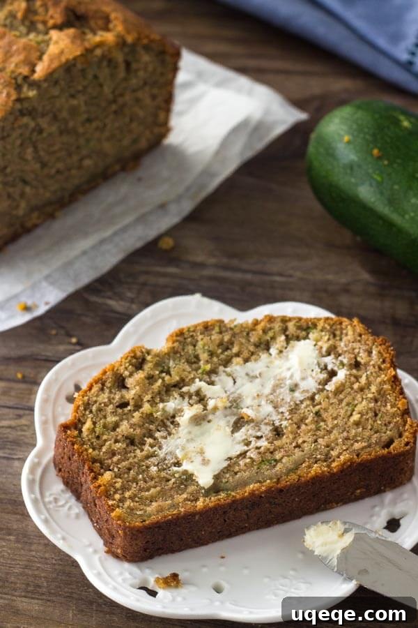 Garden Fresh Zucchini Banana Loaf 6 A perfectly sliced piece of zucchini banana bread on a white plate, generously slathered with butter, ready to be enjoyed.