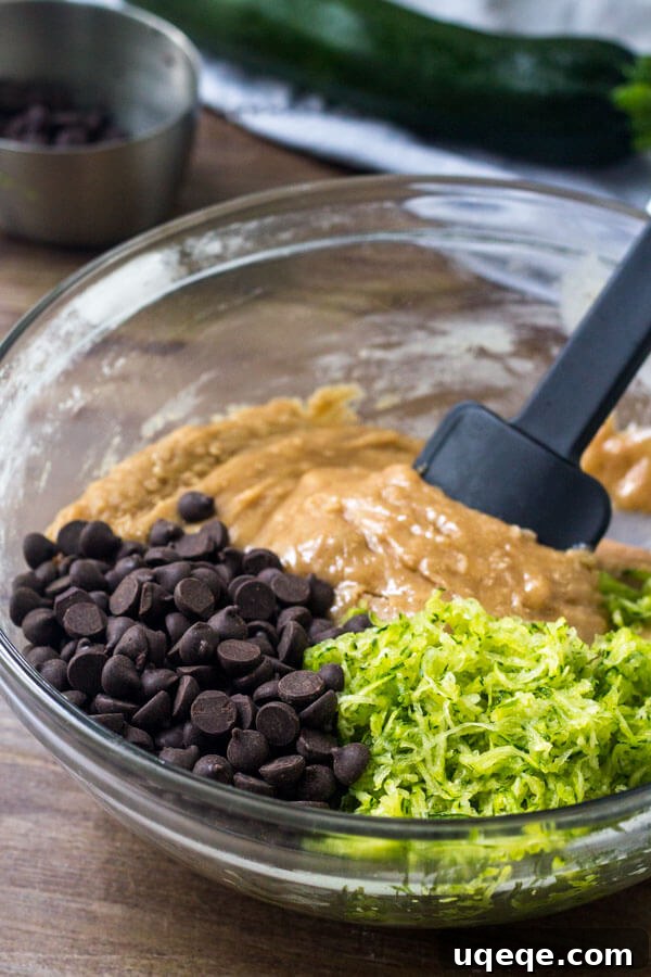 Decadent Chocolate Chip Zucchini Loaf 4 Freshly grated zucchini being patted dry with a paper towel, a crucial step for achieving perfectly moist chocolate chip zucchini bread.
