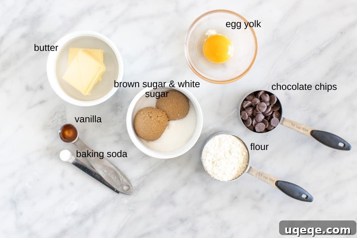 My Personal Chocolate Chip Cookie Indulgence 4 A selection of high-quality ingredients meticulously laid out on a clean surface, including melted butter, both brown and white sugars, a separated egg yolk, pure vanilla extract, all-purpose flour, baking soda, and a generous portion of chocolate chips, all ready to create the perfect single chocolate chip cookie.