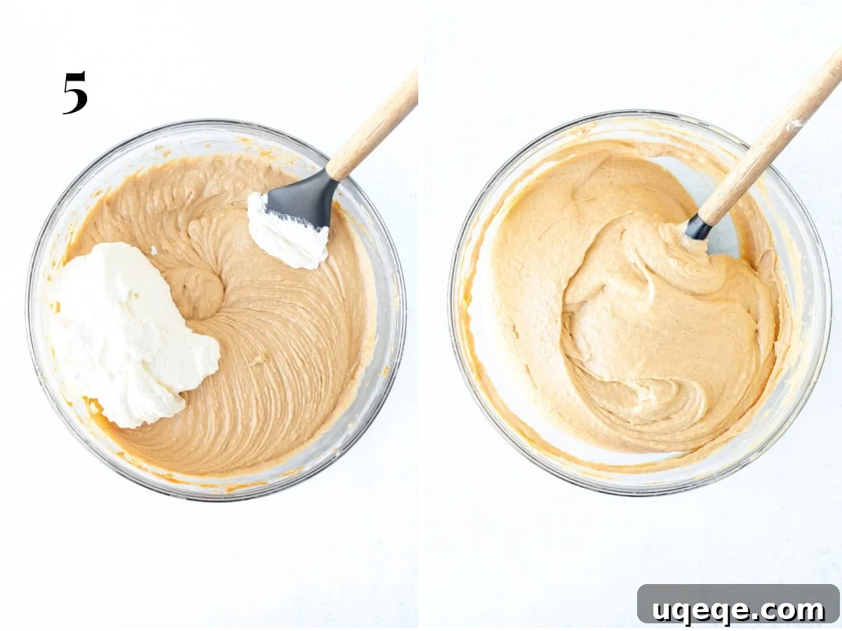 Velvety No-Bake Pumpkin Cheesecake 7 A close-up shot showing the gentle process of folding whipped cream into the no-bake pumpkin cheesecake filling using a rubber spatula, creating a smooth, uniform mixture.