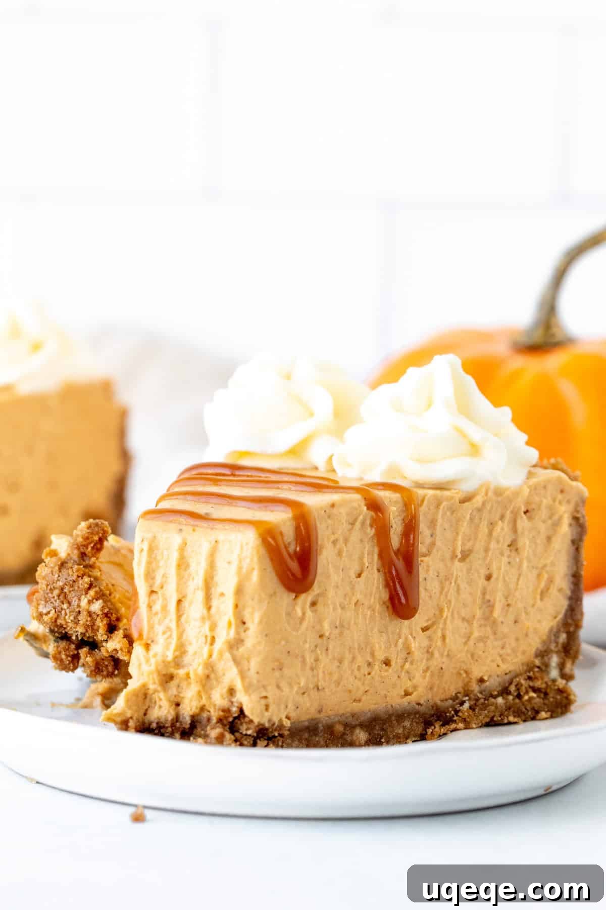 Velvety No-Bake Pumpkin Cheesecake 9 A tempting slice of no-bake pumpkin cheesecake with a visible bite taken out, highlighting its creamy texture and the golden graham crust beneath, inviting viewers to taste.