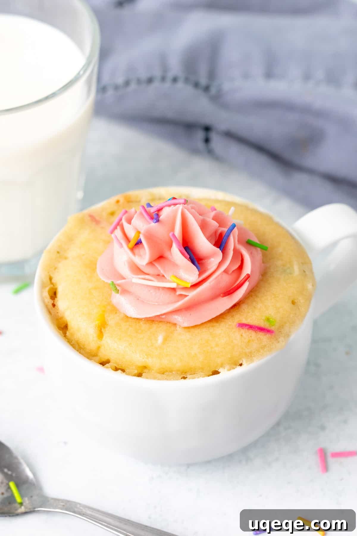 Easy Vanilla Mug Cake 2 Vanilla mug cake topped with pink frosting and sprinkles with a glass of milk