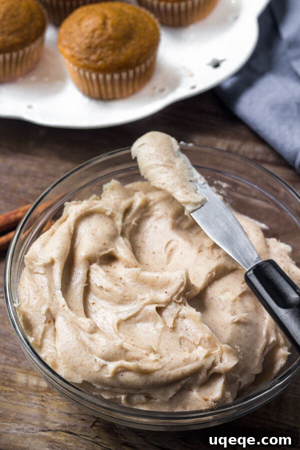Fluffy cinnamon cream cheese frosting, generously spiced with cinnamon, topping pumpkin cupcakes.