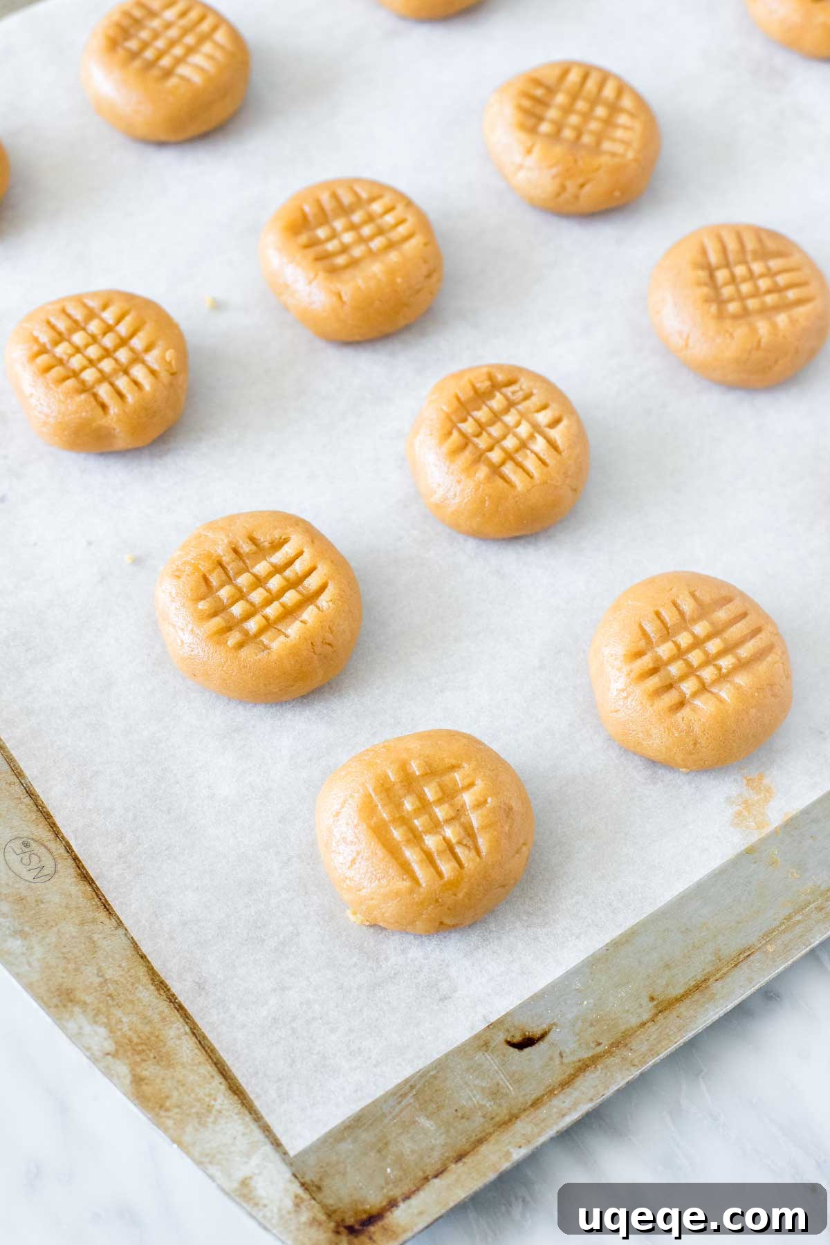 Effortless 3 Ingredient Peanut Butter Cookies 4 Peanut butter cookies on lined baking sheet before going into the oven.