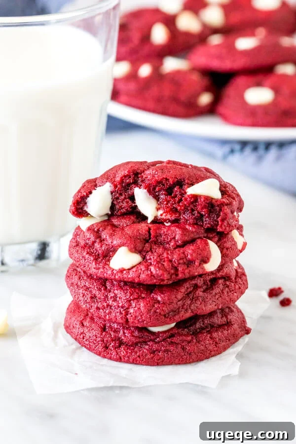 Red Velvet Cake Mix Delights 2 Stack of 4 vibrant red velvet cake mix cookies with melted white chocolate chips, alongside a refreshing glass of milk.