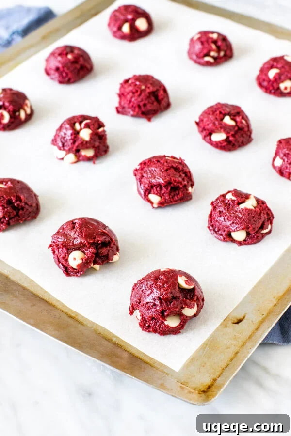 Red Velvet Cake Mix Delights 3 Lined cookie sheet showing evenly spaced balls of vibrant red velvet cookie dough, ready for baking.