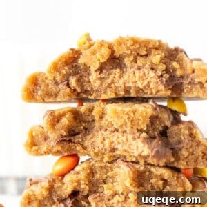 Peanut butter cookies stuffed with a peanut butter cup in the middle, broken in half and stacked on top of one another, showcasing the delightful filling.