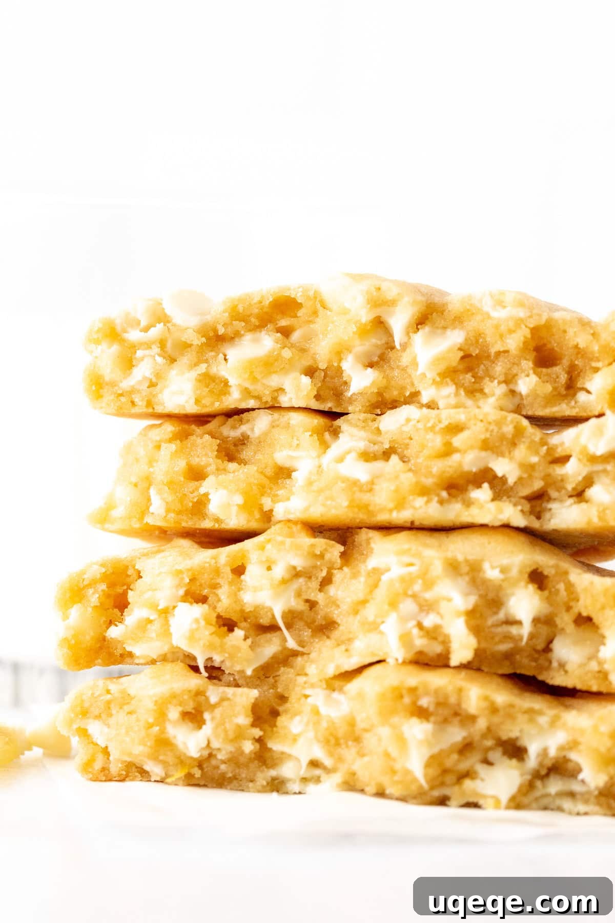 Zesty Lemon White Chocolate Delights 2 Lemon white chocolate chip cookies, broken in half and stacked on top of one another, showcasing their thick, chewy texture and abundant white chocolate chips