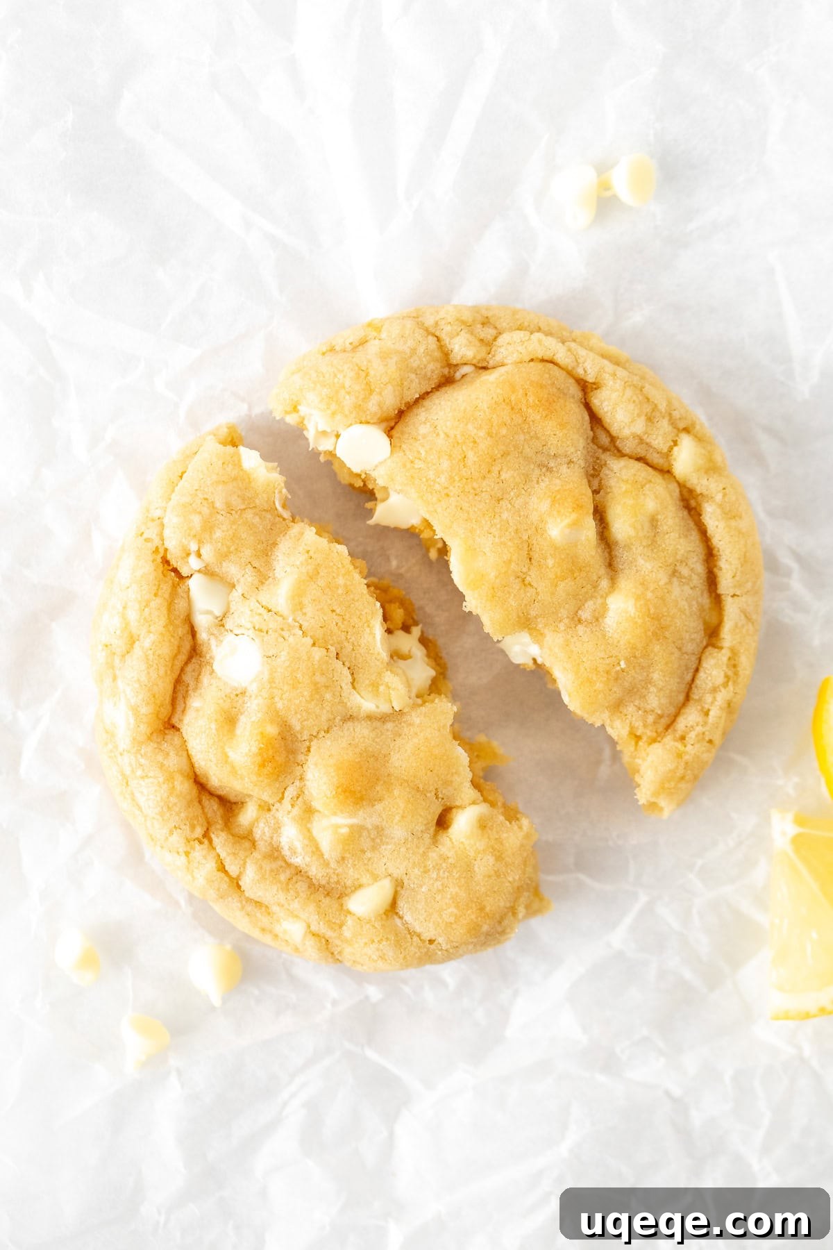 Zesty Lemon White Chocolate Delights 4 Close-up of a lemon white chocolate chip cookie, broken in half to reveal its soft, thick interior and melted white chocolate chips