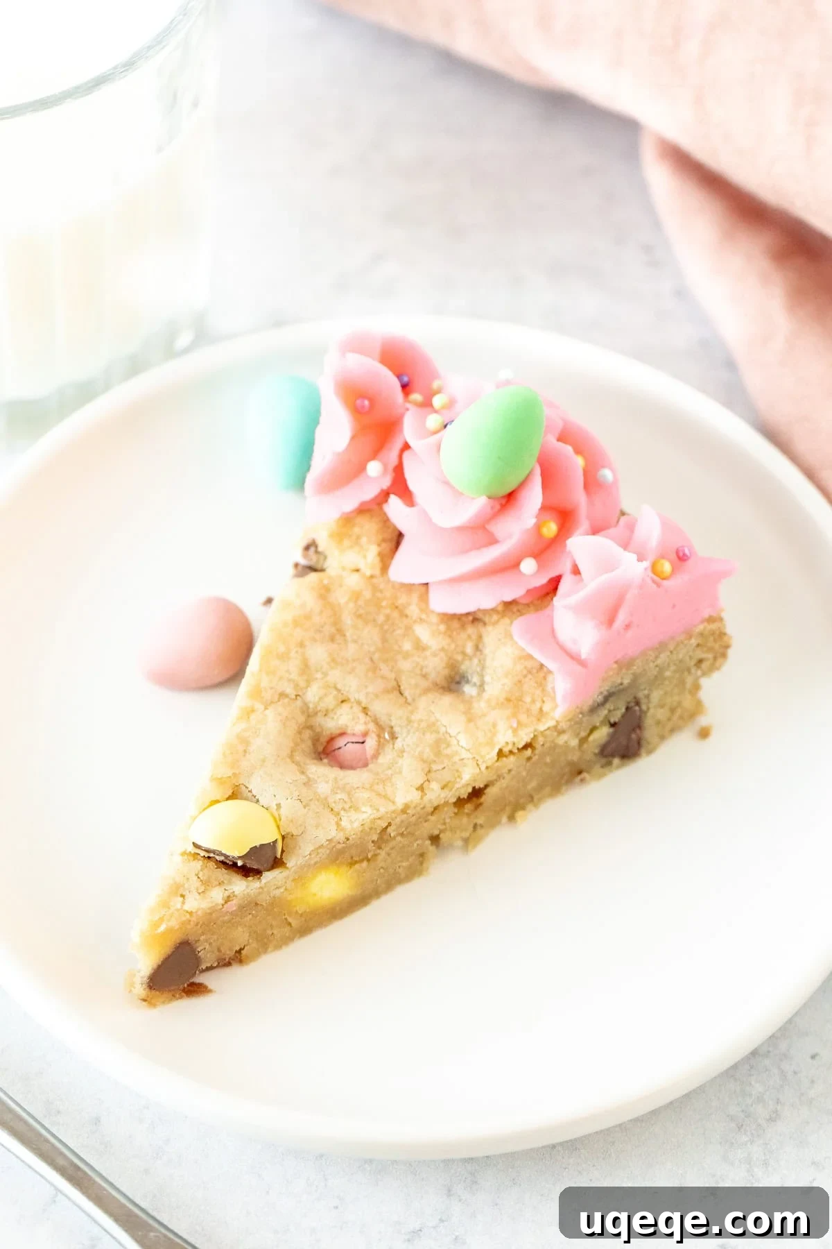 Easter Cookie Cake Delight 4 Close-up of a slice of Easter cookie cake decorated with vibrant pink frosting and a single chocolate egg candy.