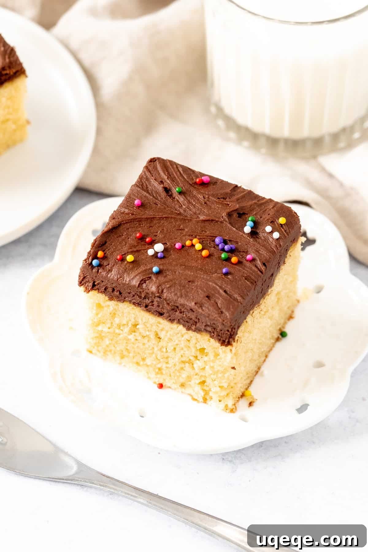 Sunshine Yellow Sheet Cake with Velvety Chocolate Frosting 9 Square slice of golden yellow cake with chocolate frosting and a glass of milk