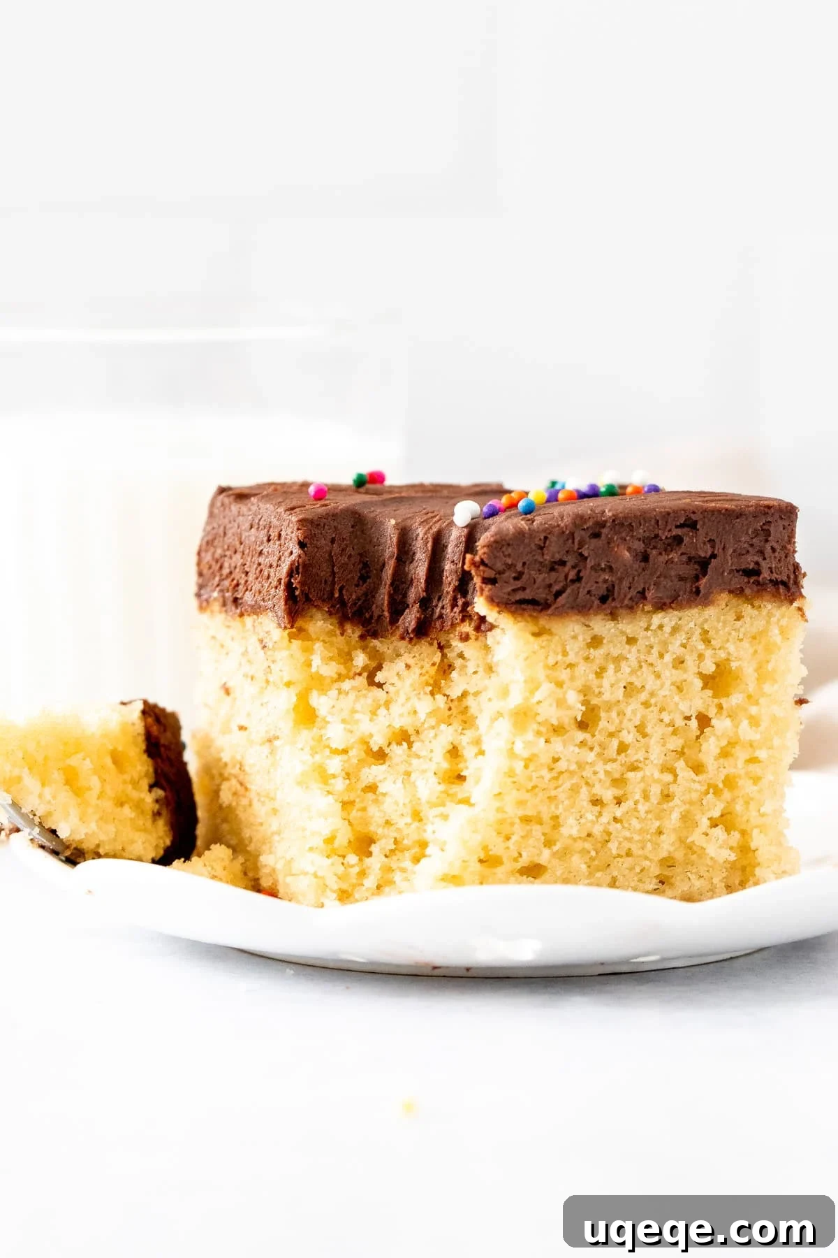 Sunshine Yellow Sheet Cake with Velvety Chocolate Frosting 10 Slice of golden cake with chocolate frosting, with a bite taken out, showing the moist crumb