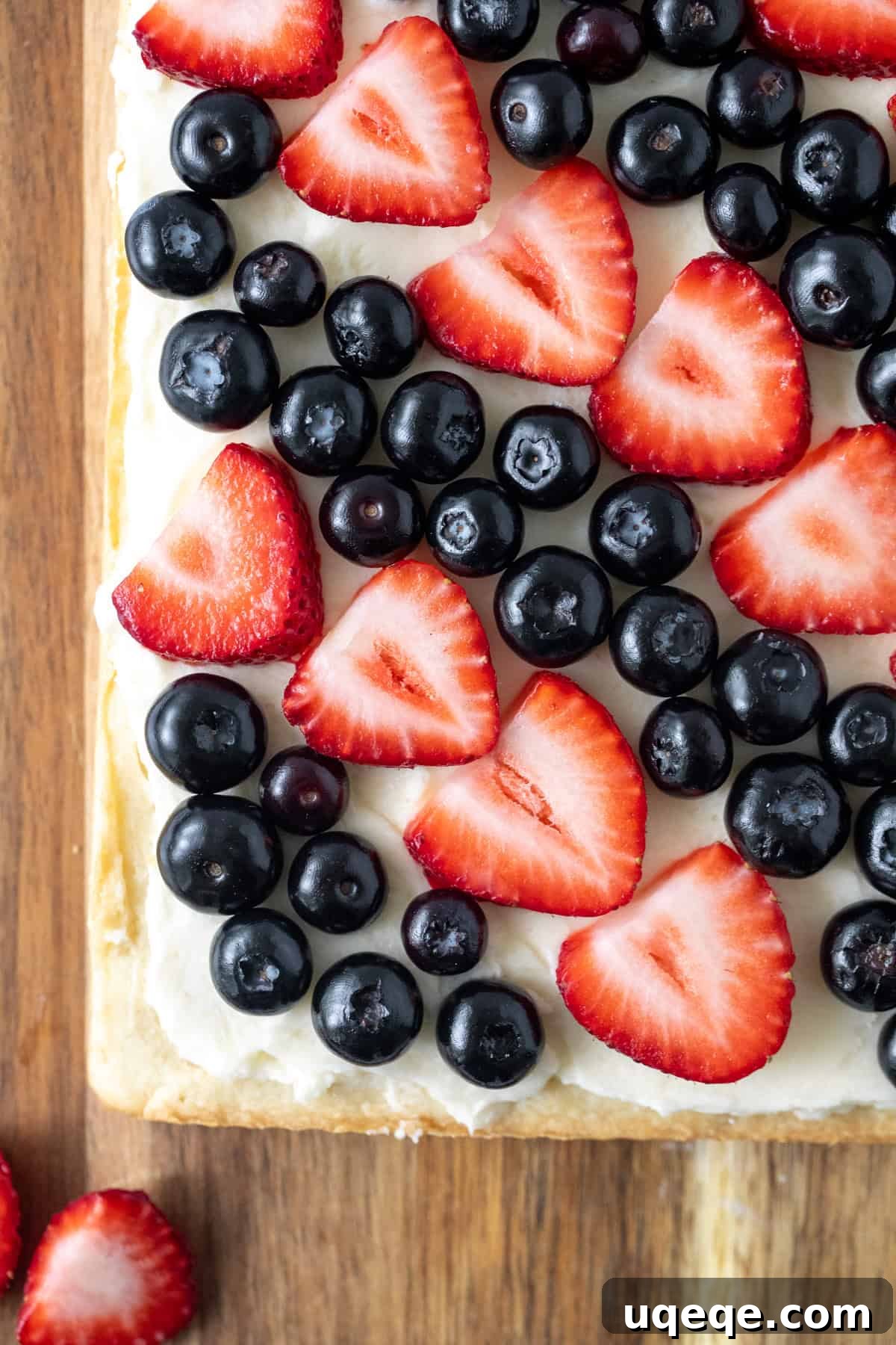 Slab of sugar cookie bars with vanilla frosting and topped with blueberries and sliced strawberries