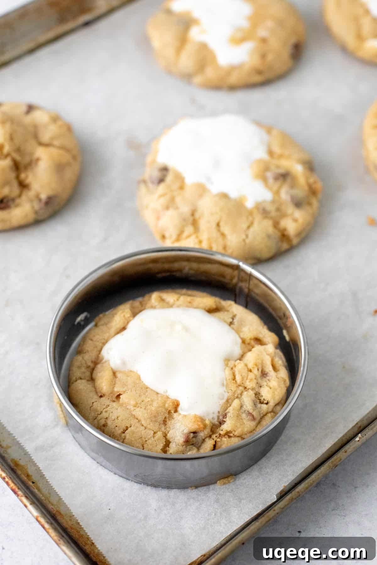 Gooey S'mores Cookies with Chocolate & Toasted Marshmallow 6 S'mores cookies on a cookie sheet with a round cookie cutter around the cookie.