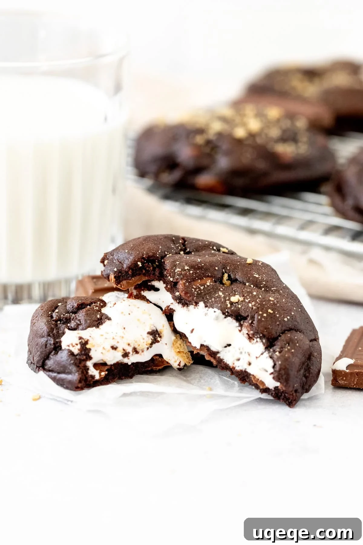 chocolate cookie stuffed with marshmallow, broken in half with a glass of milk